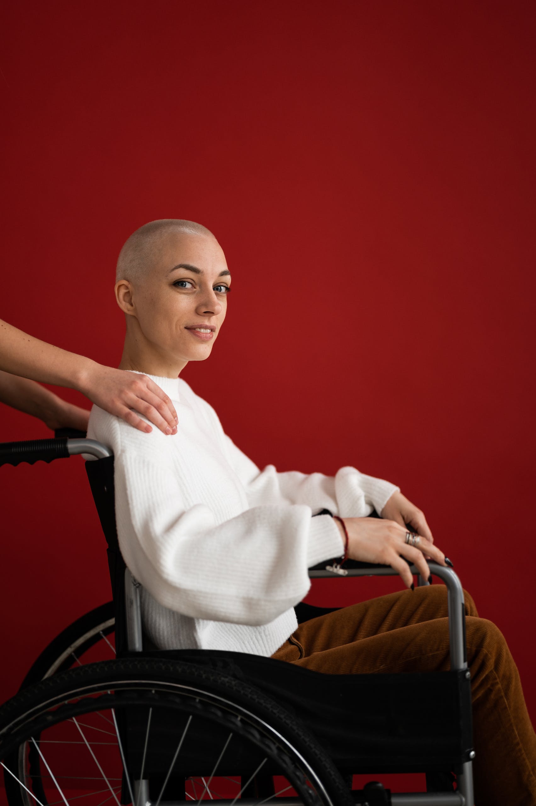 Crop assistant supporting smiling patient in wheelchair during rehabilitation process